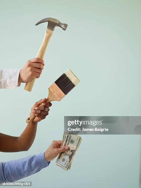 three people holding paintbrush, hammer and money, close-up of hands - martillo herramienta de mano fotografías e imágenes de stock