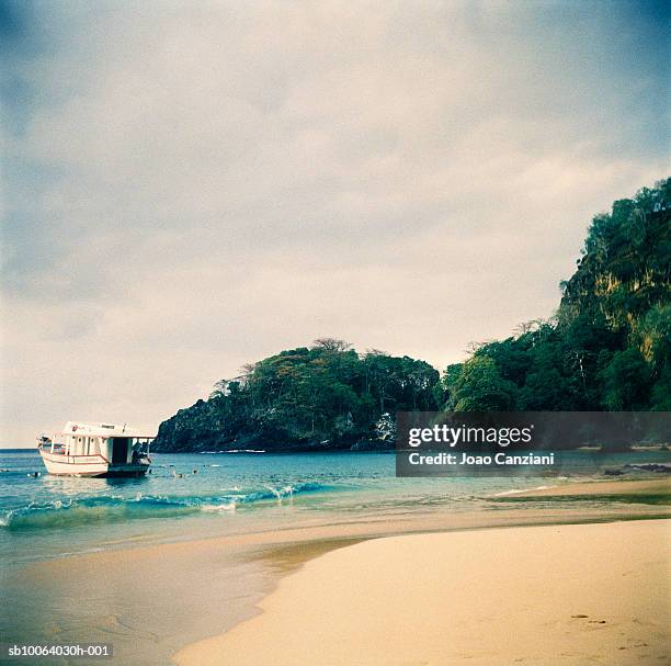 boat anchored by seashore - baía do sancho stock pictures, royalty-free photos & images