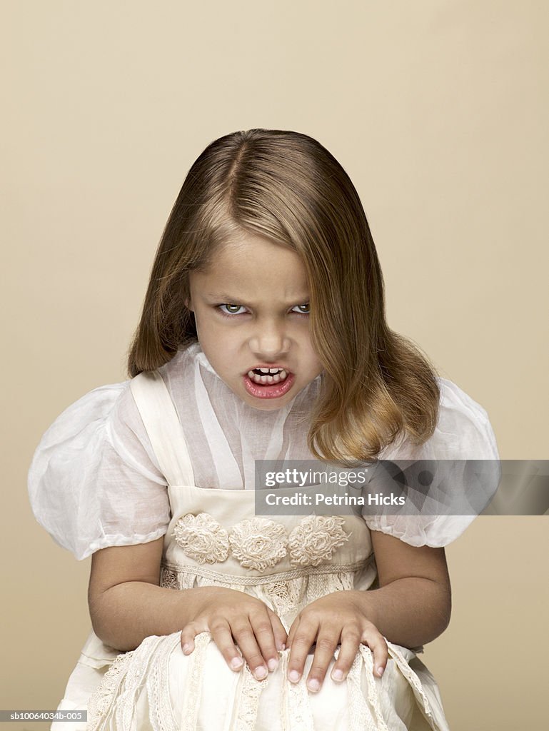 Portrait of girl (4-5) growling, sitting in studio