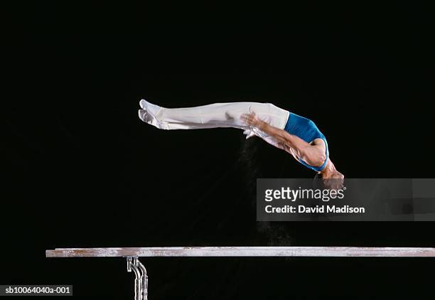 male gymnast performing on parallel bars - male gymnast stockfoto's en -beelden