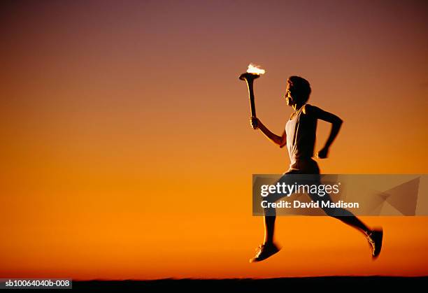 silhouette of man running with torch at sunset - course sur piste hommes photos et images de collection