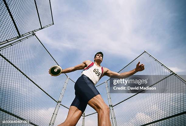 man preparing to throw discus at track, low angle view - discus photos et images de collection
