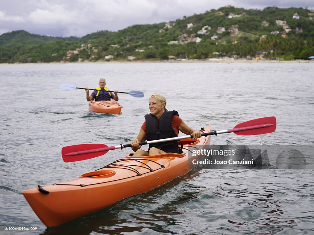 Woman kayaking, man in background