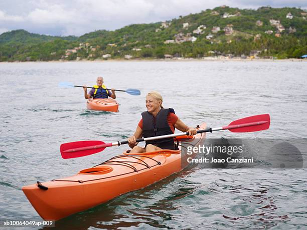 woman kayaking, man in background - kayaker woman stock pictures, royalty-free photos & images