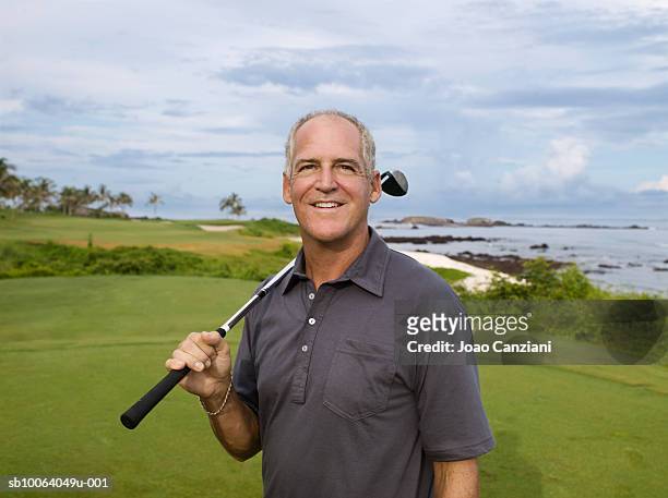 mature man with club in golf course by sea, portrait - golf short iron stock pictures, royalty-free photos & images