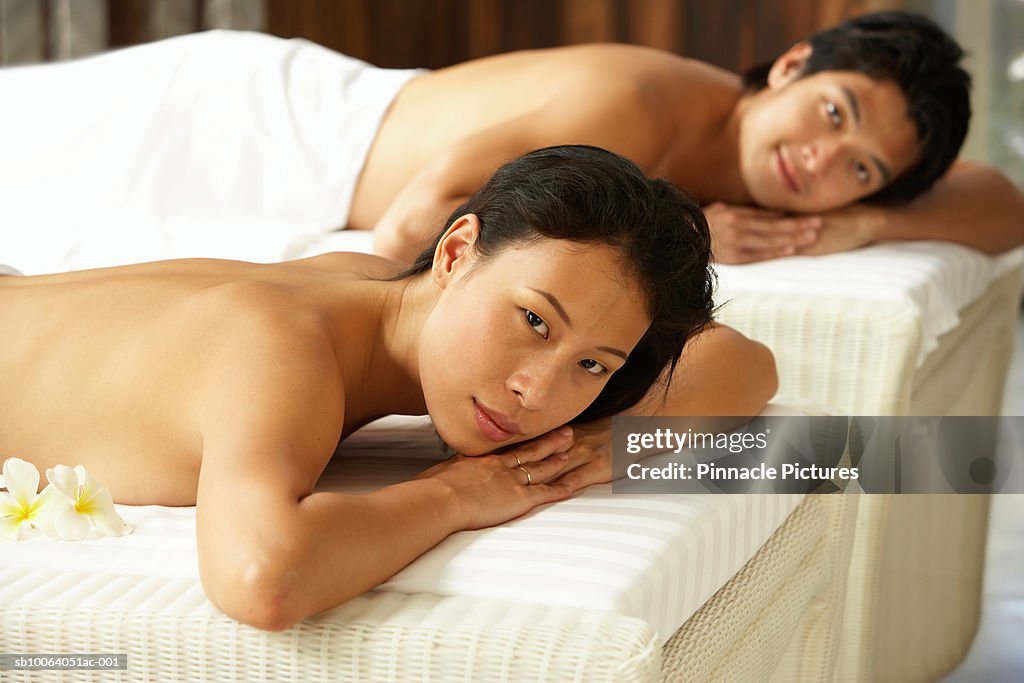 Young man and woman lying on massage tables, portrait