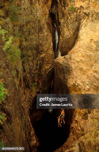 australia, victoria, man and boy (6-7) jumping from rocks in werribee gorge - werribee gorge stock pictures, royalty-free photos & images