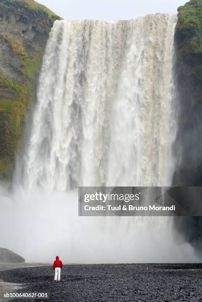 man watching skogarfoss waterfall, rear view - skogafoss waterfall stock pictures, royalty-free photos & images