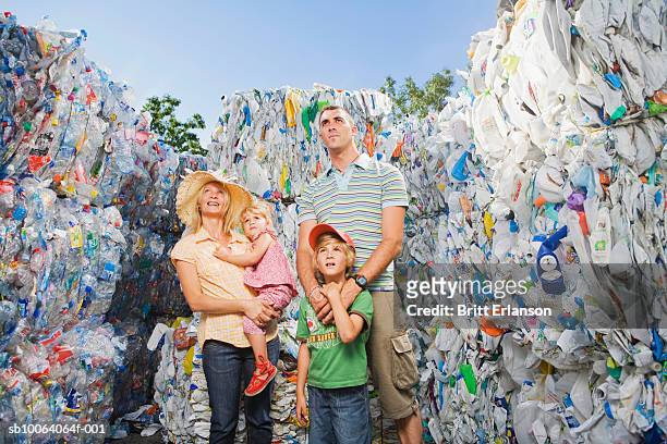 family standing amongst recycled materials, smiling - omgeven stockfoto's en -beelden