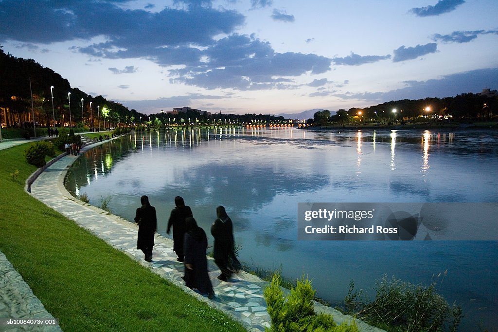 Iran, Esfahan, women in chadors walking along Zayandeh River at evening