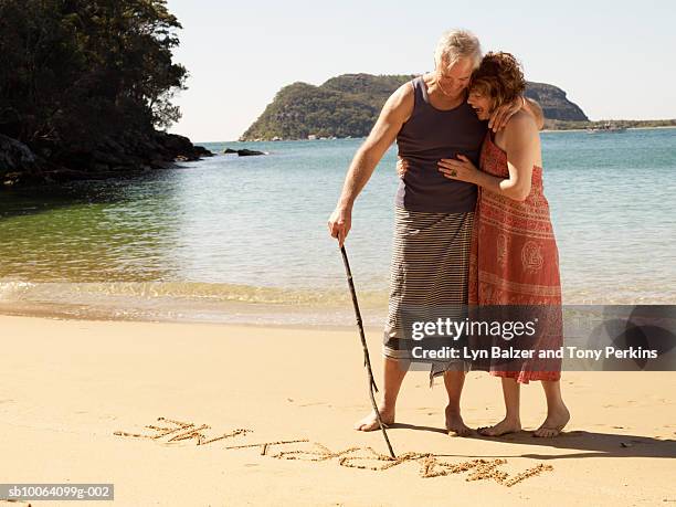 mature couple drawing on sand, saying marry me - sarong stock pictures, royalty-free photos & images