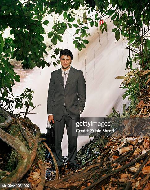 businessman standing in rainforest, smiling - anzug ausland stock-fotos und bilder