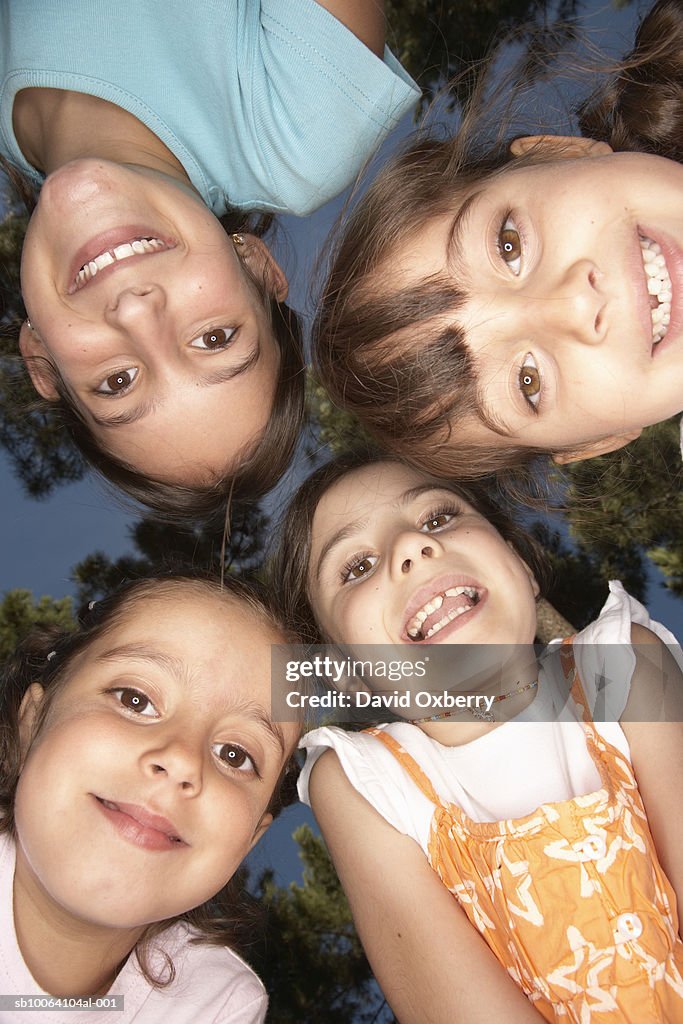 Four kids (5-9) in huddle outdoors, portrait, view from below