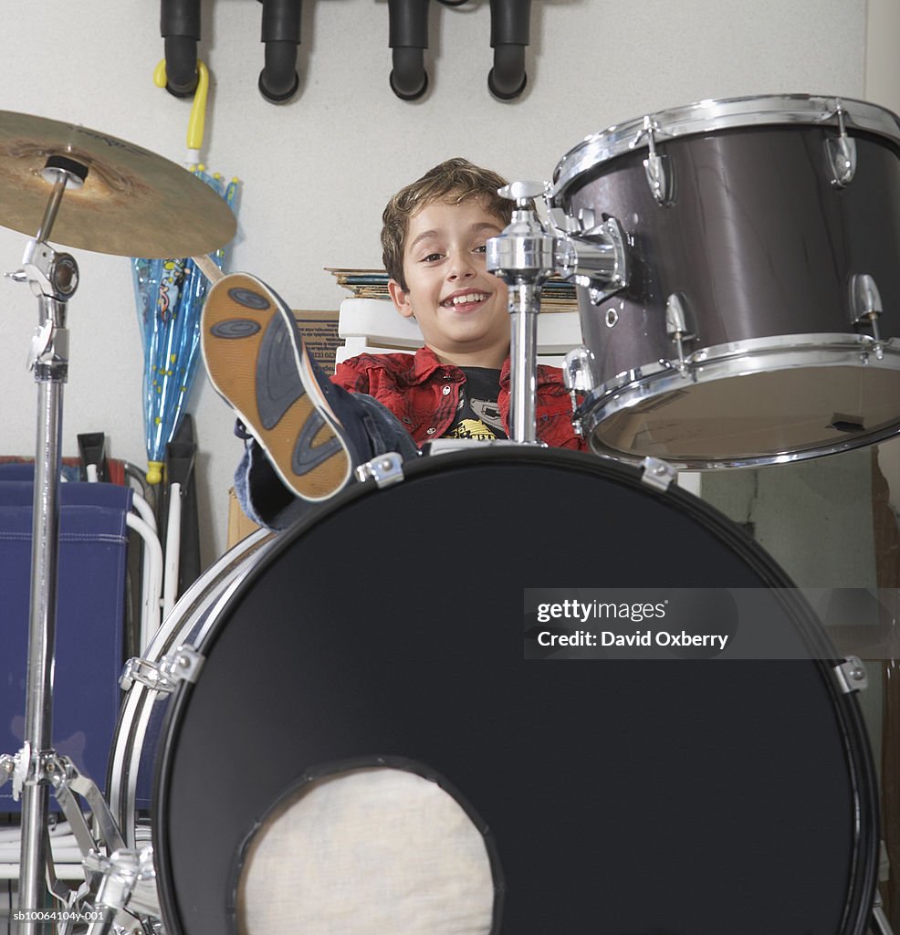 Boy (10-11) sitting behind drum kit, portrait