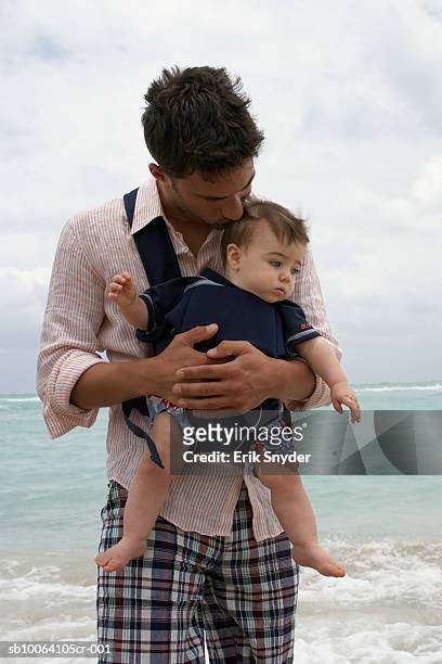 father carrying baby daughter (15-18 months) on beach - strap stock pictures, royalty-free photos & images