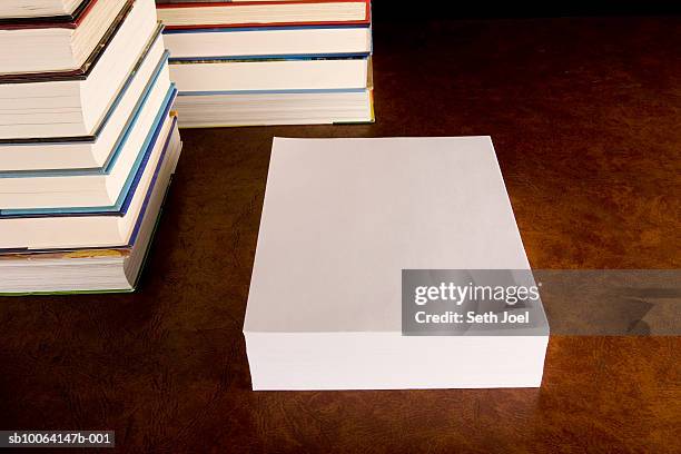 two stacks of hard cover books on desk with ream of clean white paper - ream of paper stock pictures, royalty-free photos & images