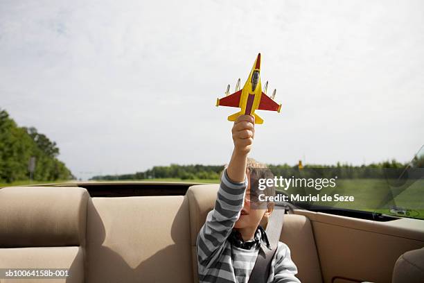 boy (6-7) playing with airplane in back of convertible - boy playing with cars stock pictures, royalty-free photos & images