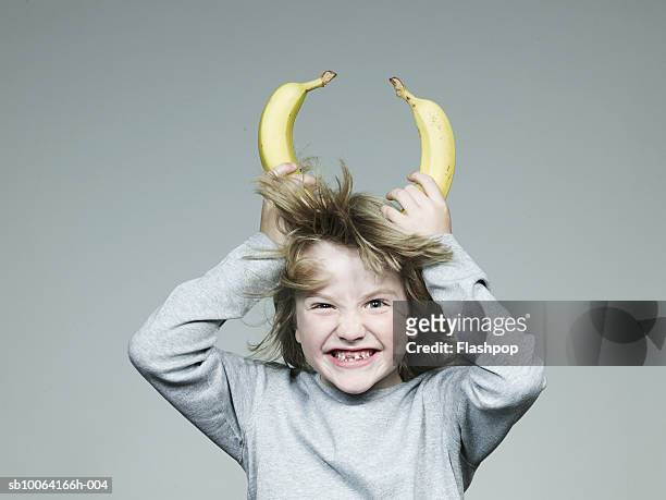 boy (6-7) holding two banana on head, smiling, close-up - sinful pleasures stockfoto's en -beelden