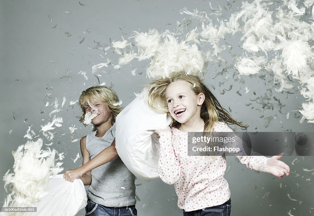 Boy and girl (6-9) playing pillow fight