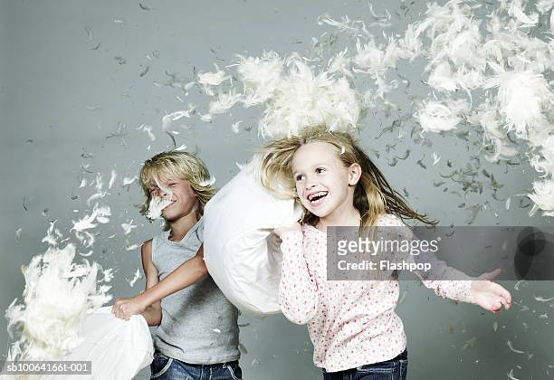 boy and girl (6-9) playing pillow fight - feather floating stock pictures, royalty-free photos & images