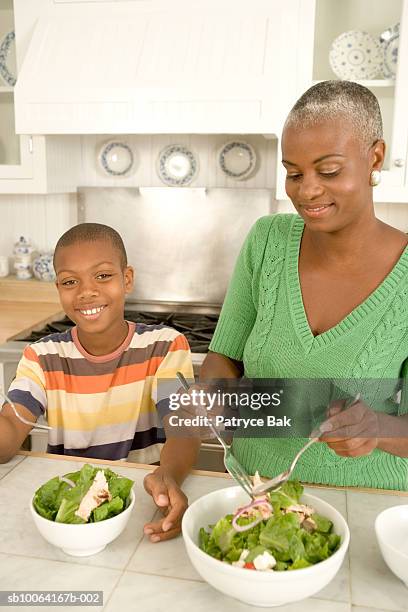 mother and son (10-11) preparing salad in kitchen, smiling - salad server stock pictures, royalty-free photos & images