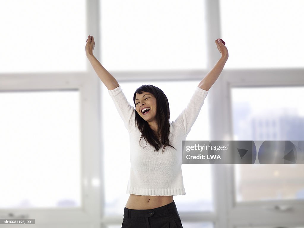 Woman stretching arms, eyes closed, laughing