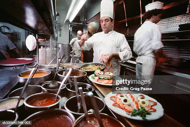 chef plating dinners with staff in commercial kitchen - food plating fotografías e imágenes de stock