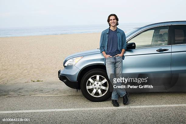 man leaning against parked car next to beach, portrait - man lean car stock-fotos und bilder