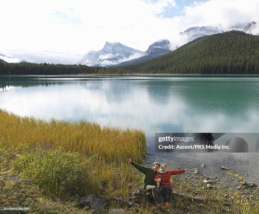 Couple sitting near lake, snowcapped mountains in background