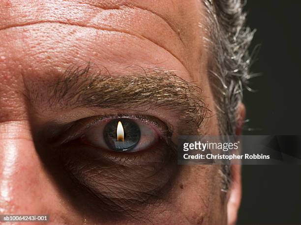 flame projected in eye of senior man, close-up - demon stock-fotos und bilder