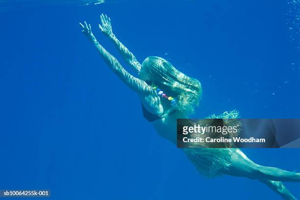 woman in bikini and hula skirt swimming, underwater view - 浮き上がる ストックフォトと画像