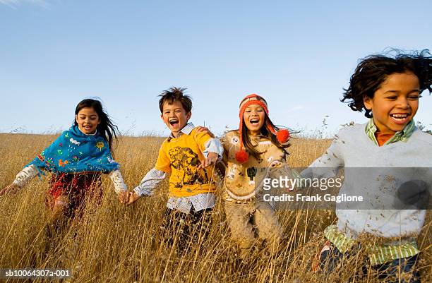 four kids (6-8) running through field - solo bambini foto e immagini stock