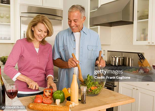 mature couple preparing salad in kitchen - middle aged couple cooking ストックフォトと画像