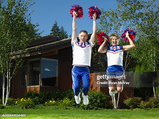 mature couple holding pom poms and jumping - cheerleader stock pictures, royalty-free photos & images