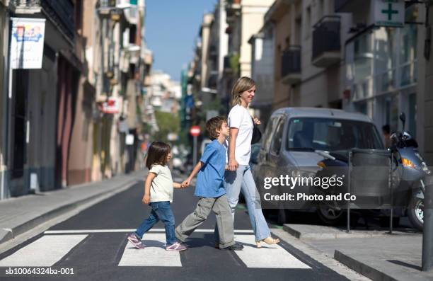 mother with children (3-7) crossing street, side view - voetganger stockfoto's en -beelden