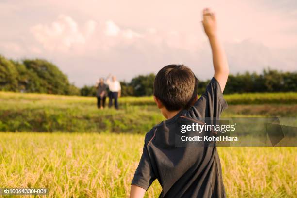 boy (6-7) waving hand to grandmother and grandfather, rear view - child waving stock pictures, royalty-free photos & images