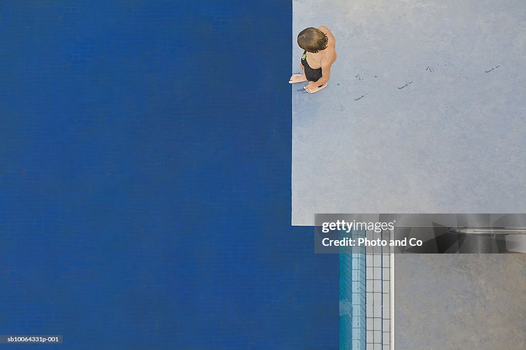 Boy (6-7) standing on diving board, overhead view