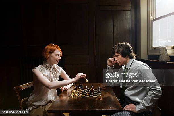 couple playing chess at table, side view - dating game stock pictures, royalty-free photos & images