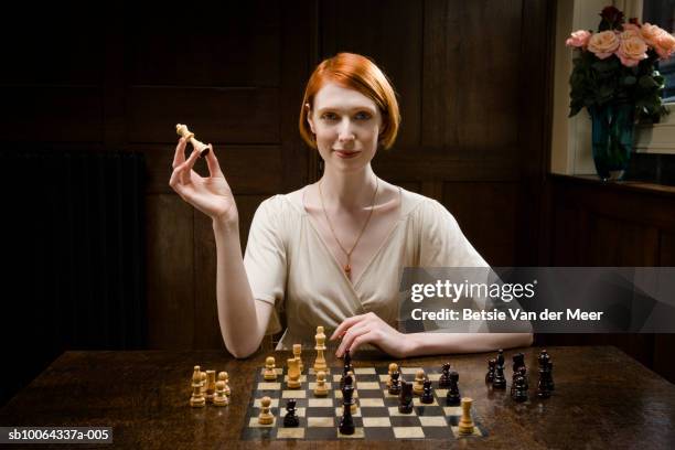 woman holding up queen chess piece, smiling, portrait - chess photos et images de collection