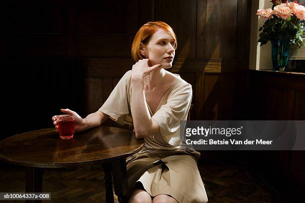 woman sitting in bar with wine glass, looking away - eleganza foto e immagini stock