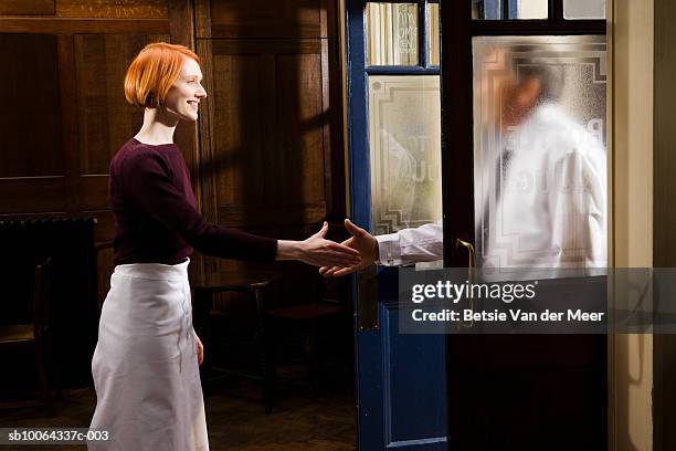 young waitress shaking hand with businessman entering bar, smiling, side view - toothy smile stock pictures, royalty-free photos & images