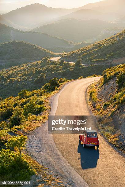 car driving on winding road at sunset, elevated view - languedoc rousillon stock-fotos und bilder