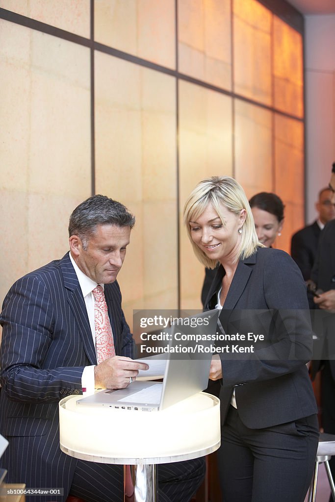 Business people in hotel lobby in front of laptop