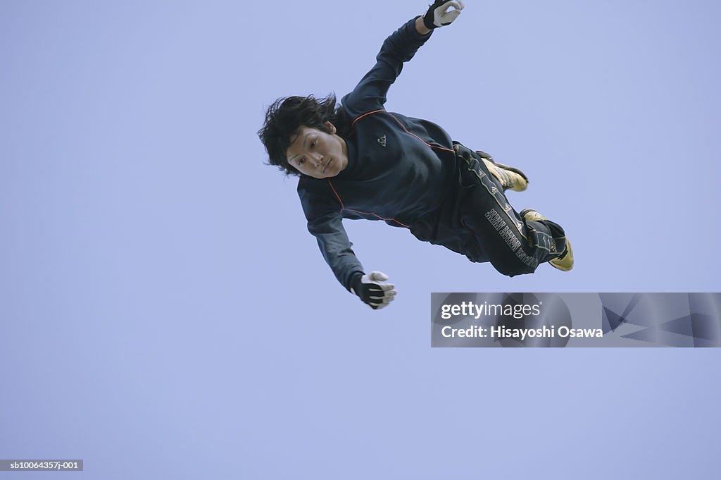 Young man flying mid-air, low angle view