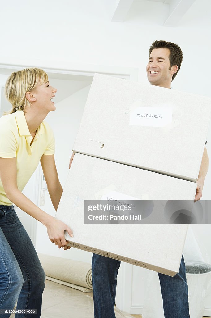 Couple carrying cardboard boxes, smiling