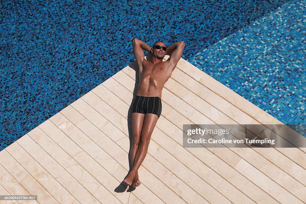 Man lying at edge of pool, elevated view