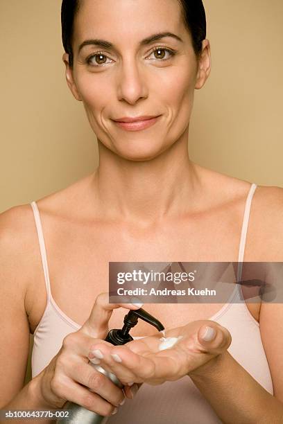 mature woman putting lotion on hand, portrait, close-up - putting lotion stock pictures, royalty-free photos & images