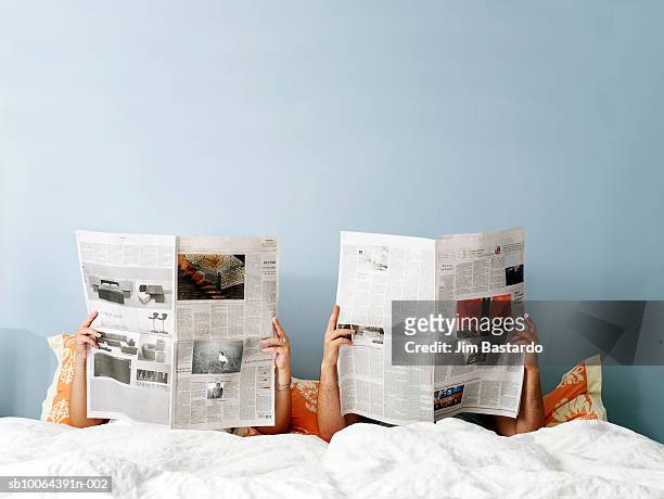 young couple reading newspaper on bed - newspaper stock pictures, royalty-free photos & images