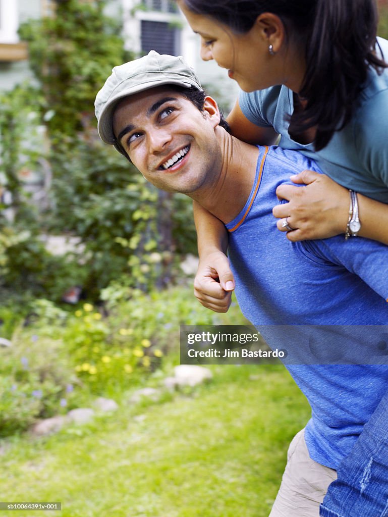 Young man carrying woman on back, smiling