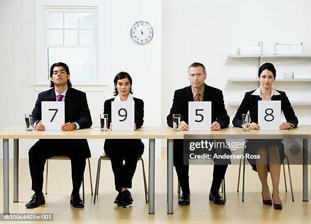 four business people sitting at desk, holding score cards, portrait - cartão de resultados imagens e fotografias de stock
